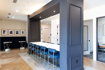 A long dark blue hallway with a row of blue chairs on one side at The Crest at South Point Apartments, Georgia